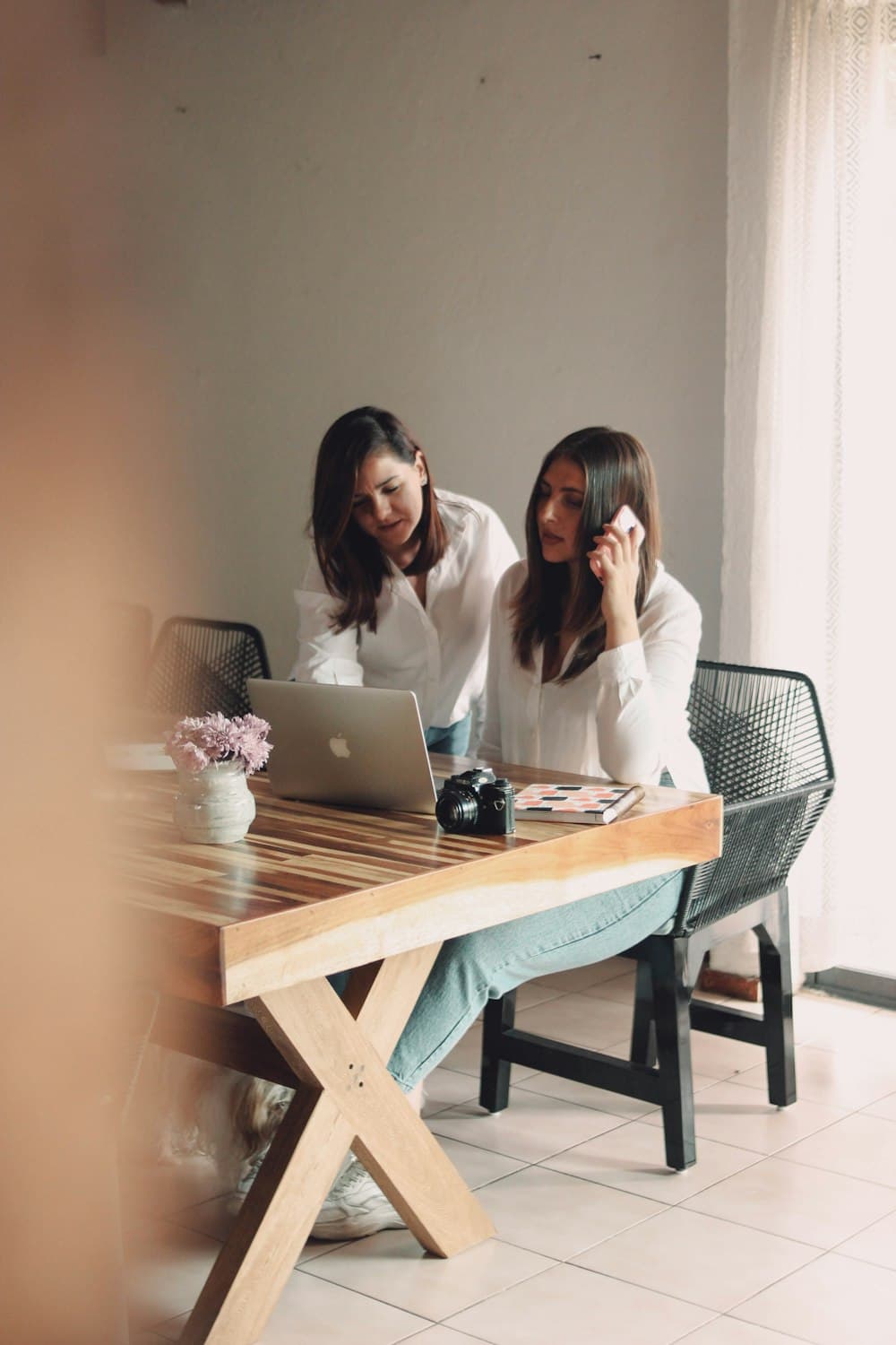 Two people reviewing plans at a laptop across a wooden table