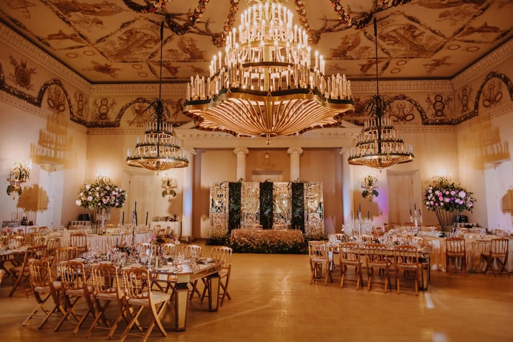 A grand ballroom set for a reception under chandeliers