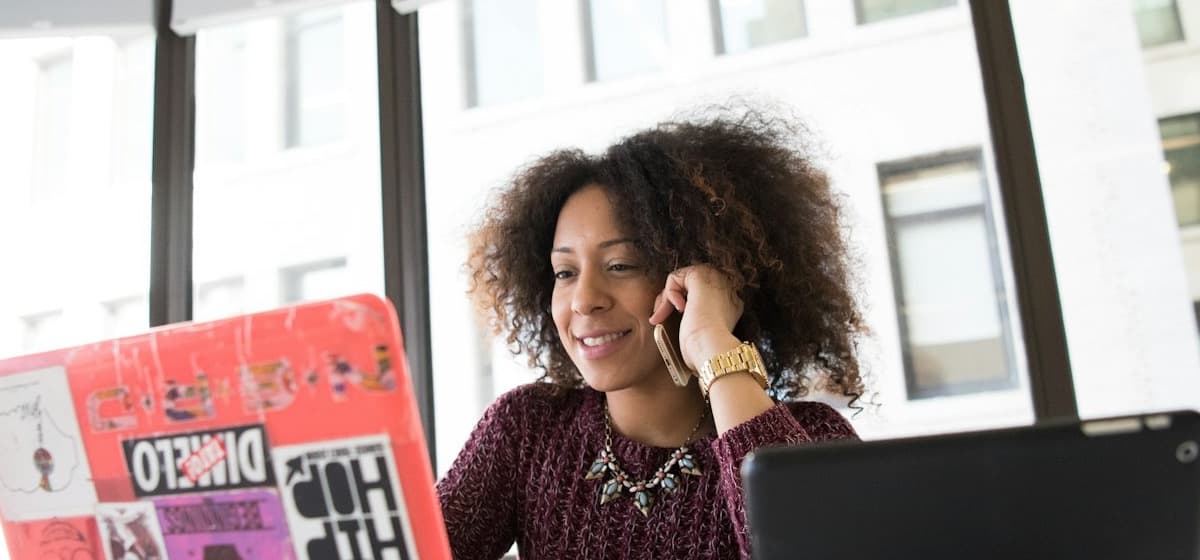 A coach at her desk taking a call beside her laptop
