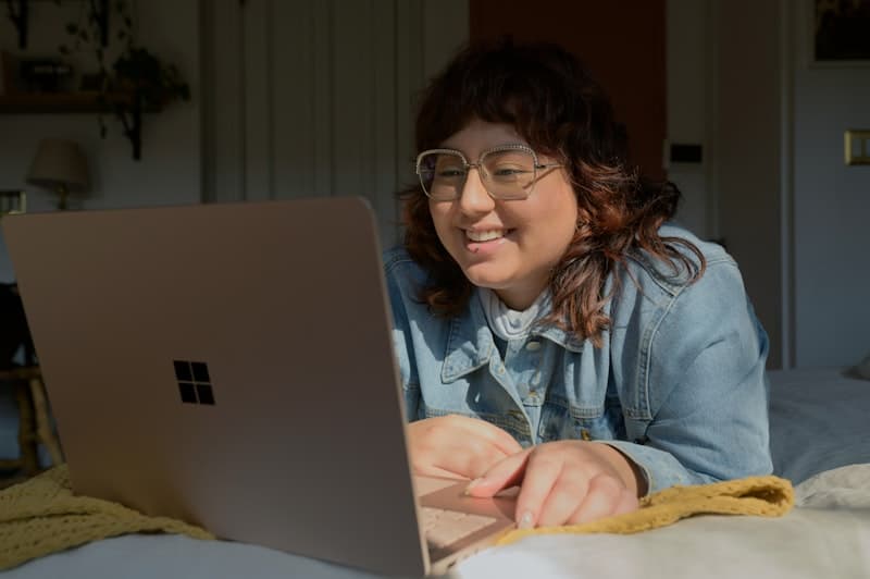 A woman in glasses working at a laptop