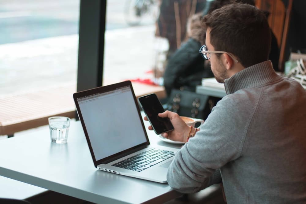 A freelancer working on a laptop by a window