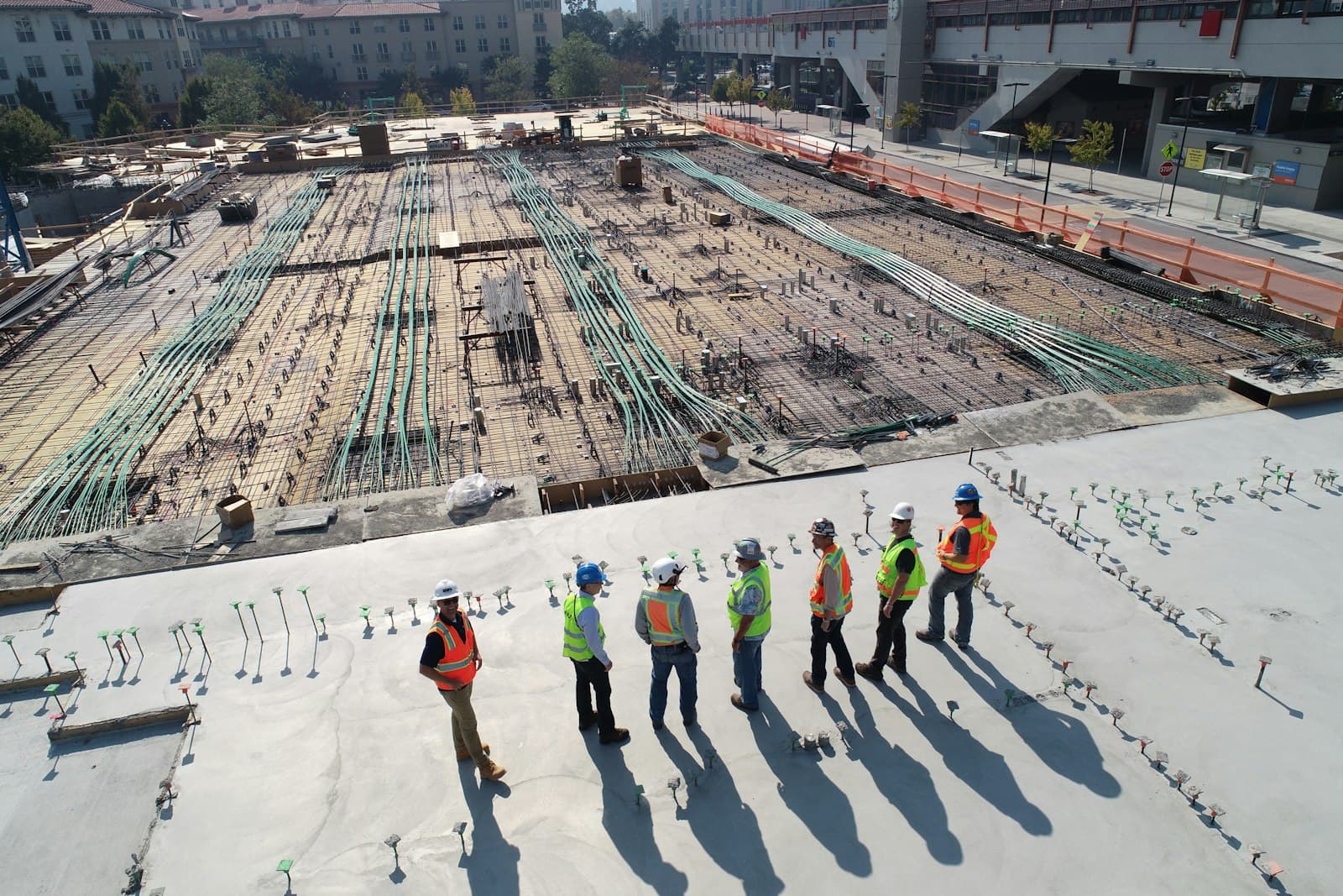 A crew in hard hats overlooking a concrete deck mid-pour