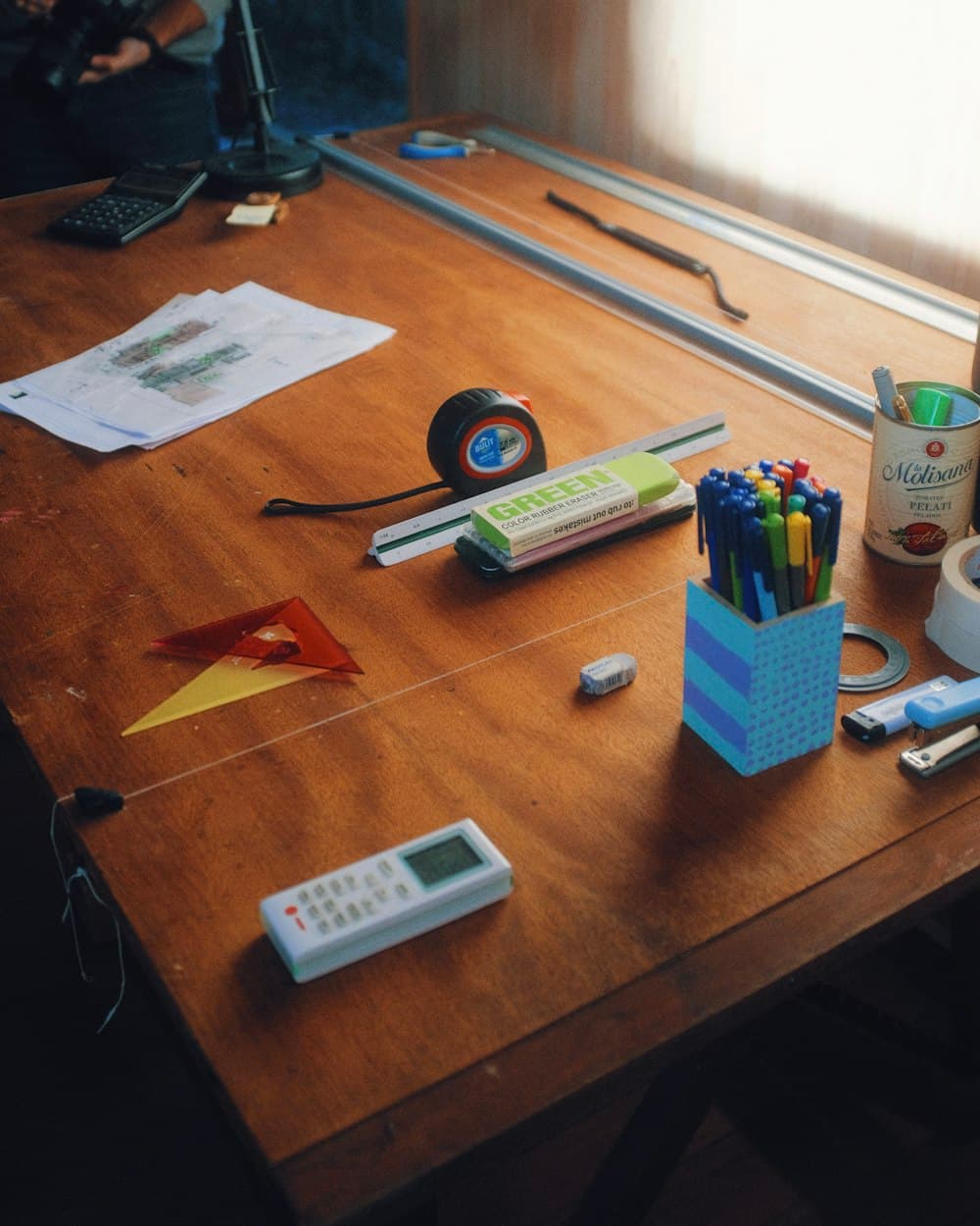 A work table with plans, tape, and measuring tools in morning light