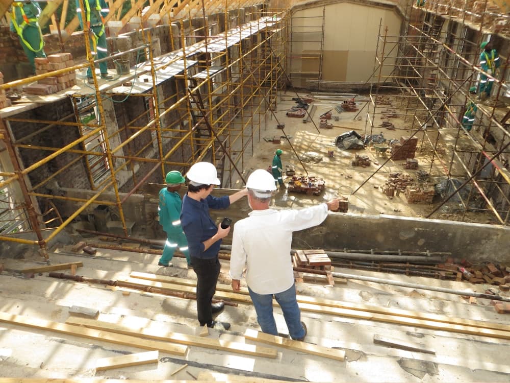 Two people in hard hats reviewing a scaffolded site