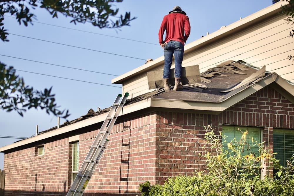 A roofer standing on the ridge of a brick house