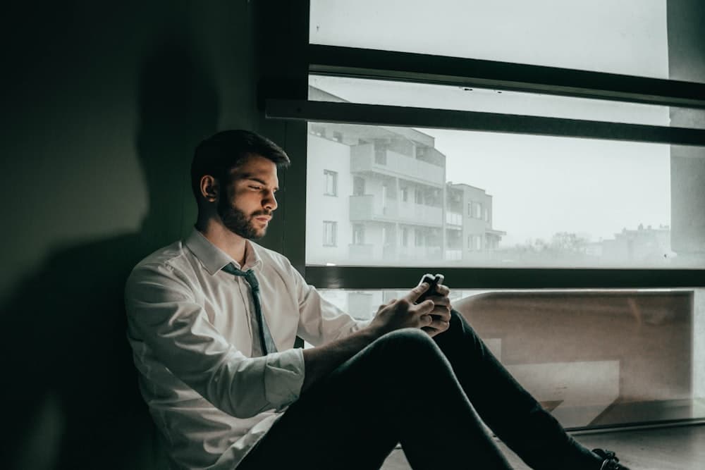 A man checking his phone by an office window