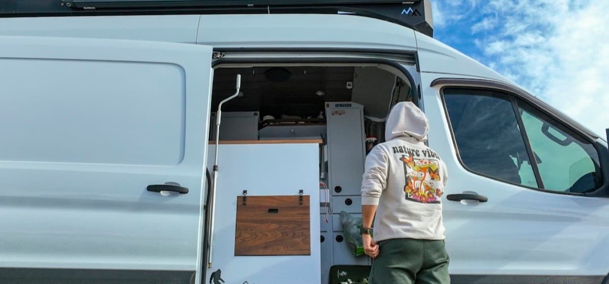 A man standing in the doorway of his work van