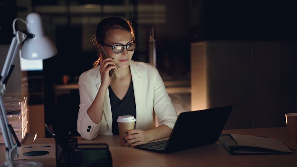 A woman on the phone at a desk with a laptop