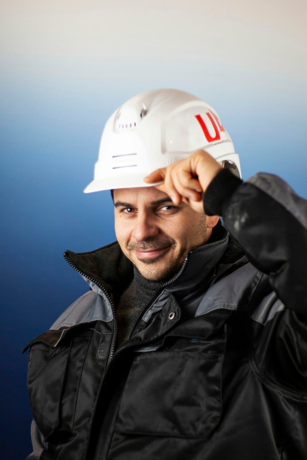 A man in a white hard hat and dark jacket