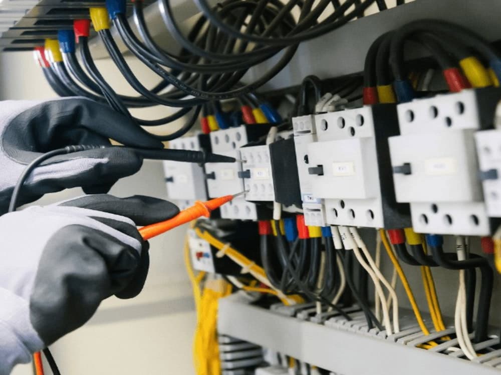 An electrician testing an electrical panel with a multimeter