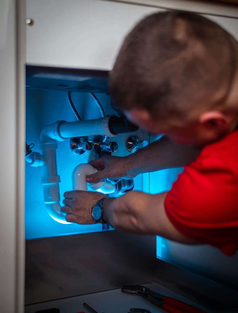 A plumber working on the trap under a sink