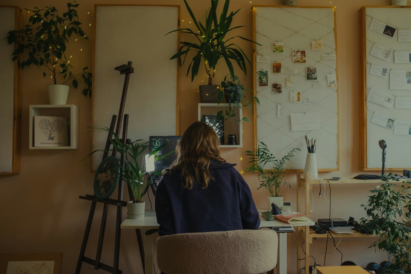 A freelancer working at a desk in a plant-filled home studio