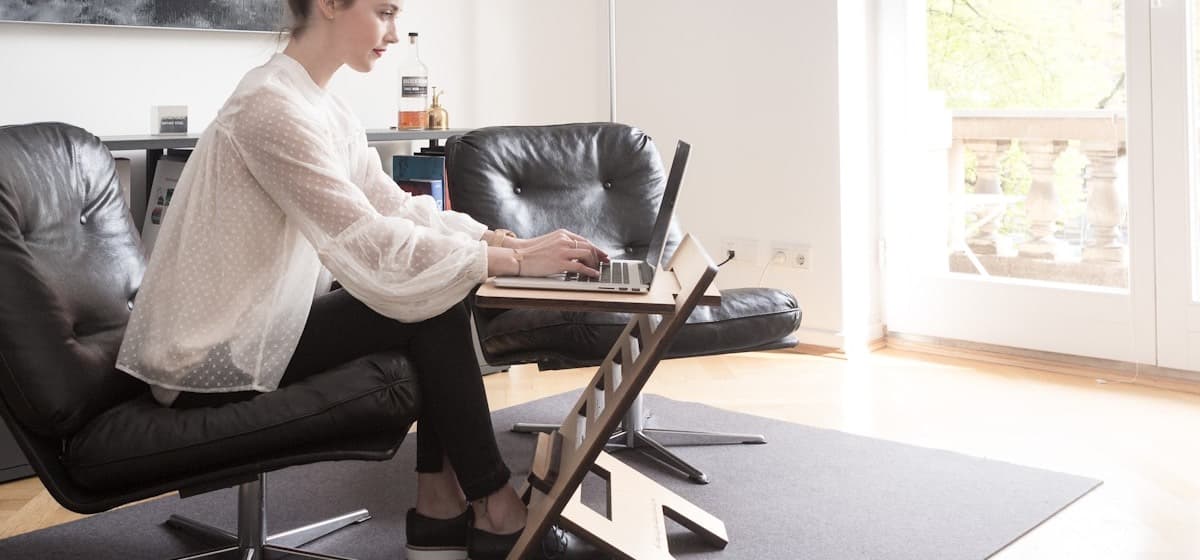 A freelancer working on a laptop in a bright living room office