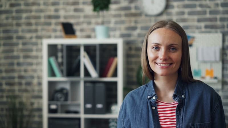 A woman in a denim shirt in a brick-walled studio
