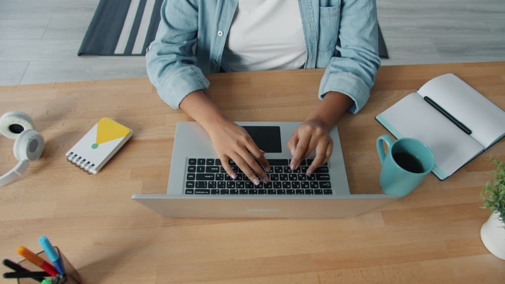 Hands typing on a laptop at a wooden desk