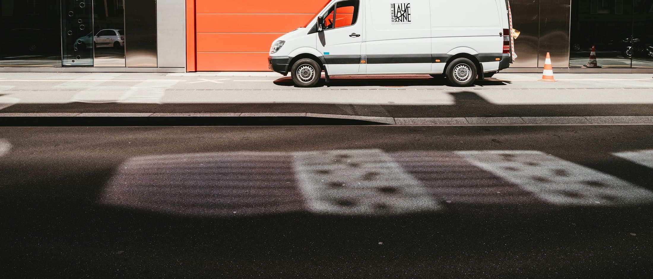 A white service van parked outside a workshop with a red door