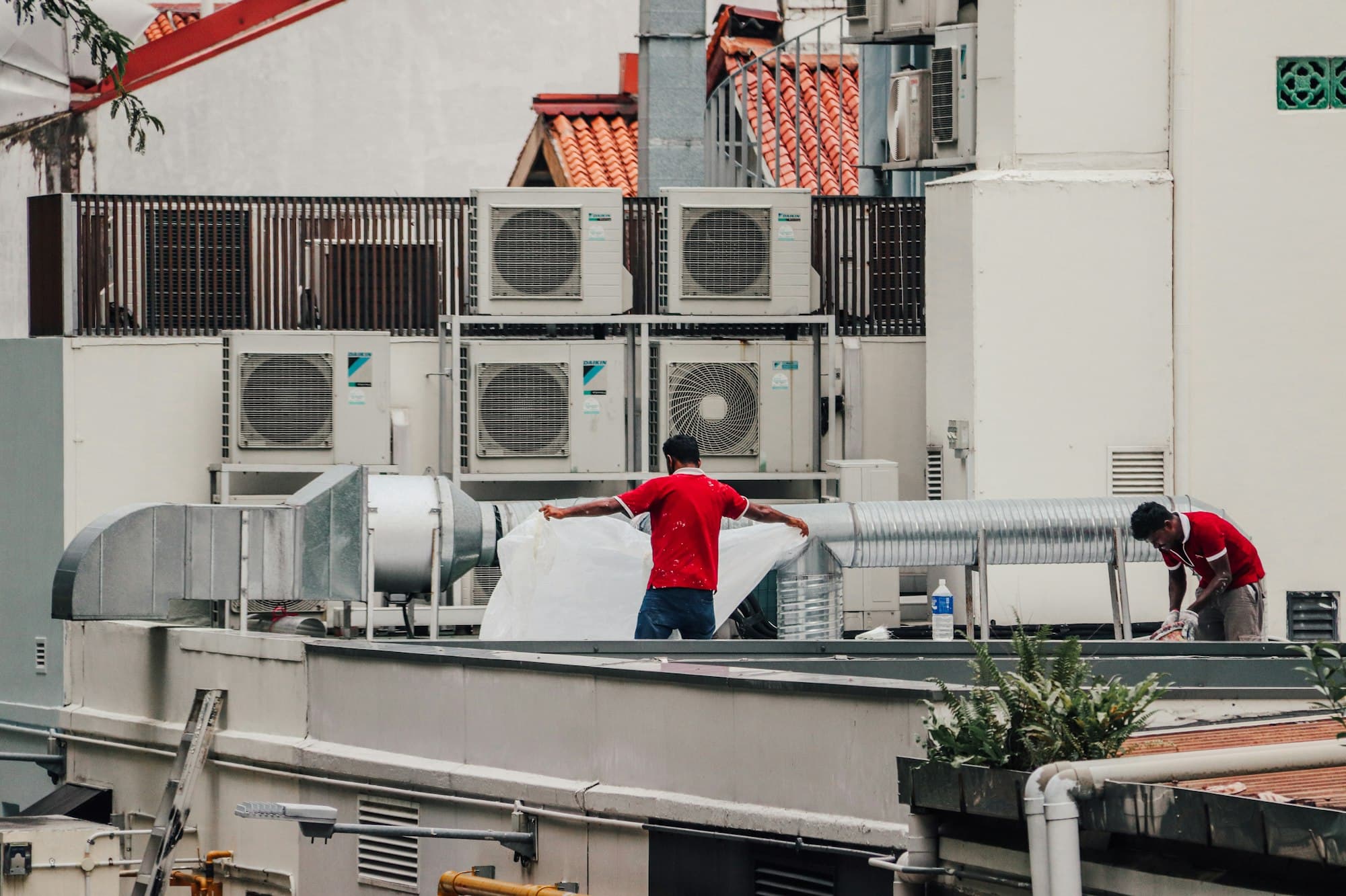 Two technicians working among rooftop air conditioning units