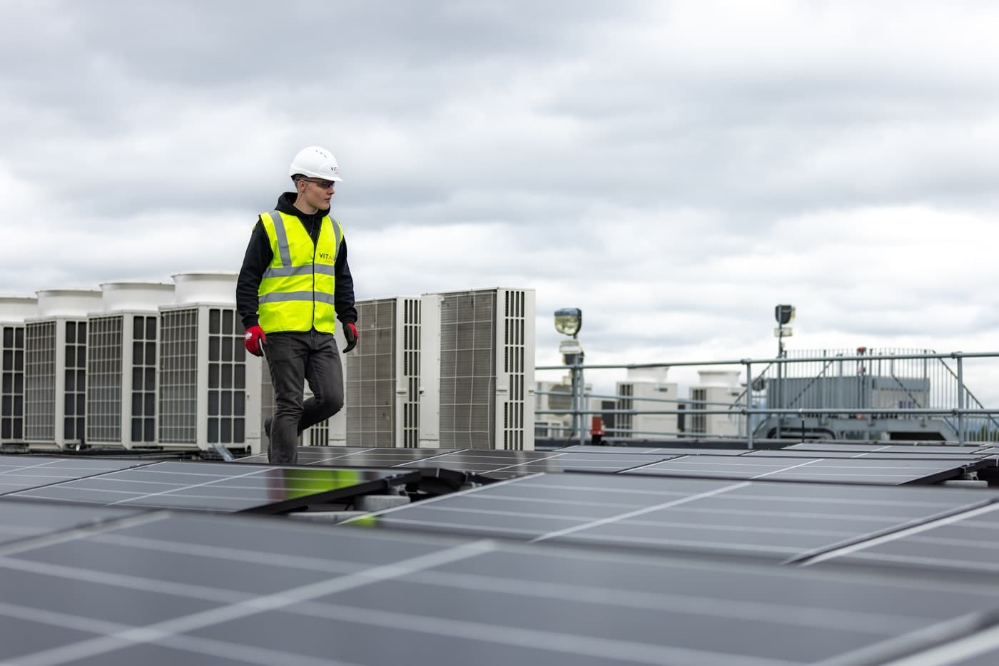 A technician walking a rooftop line of condenser units