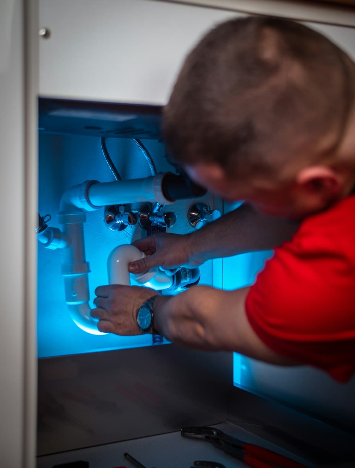 A plumber working on the trap under a sink