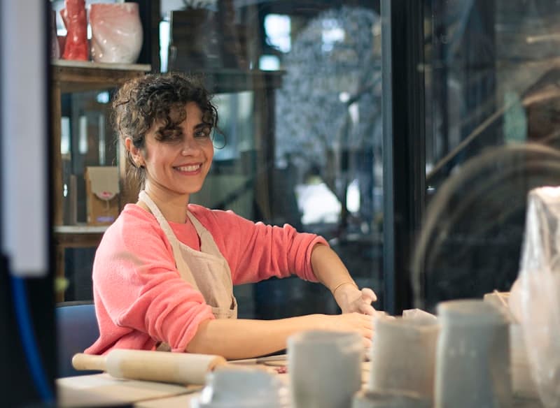 A smiling woman at a workbench in her studio