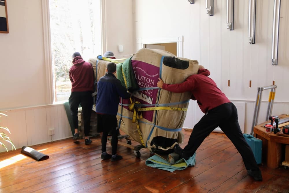 Movers carrying wrapped furniture into a home