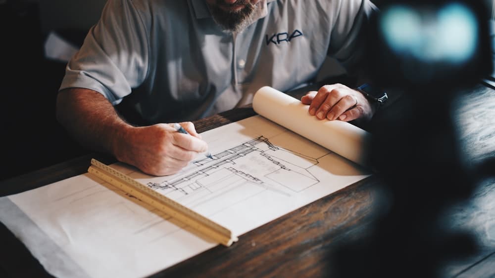 A person drafting on a sketch pad at a desk