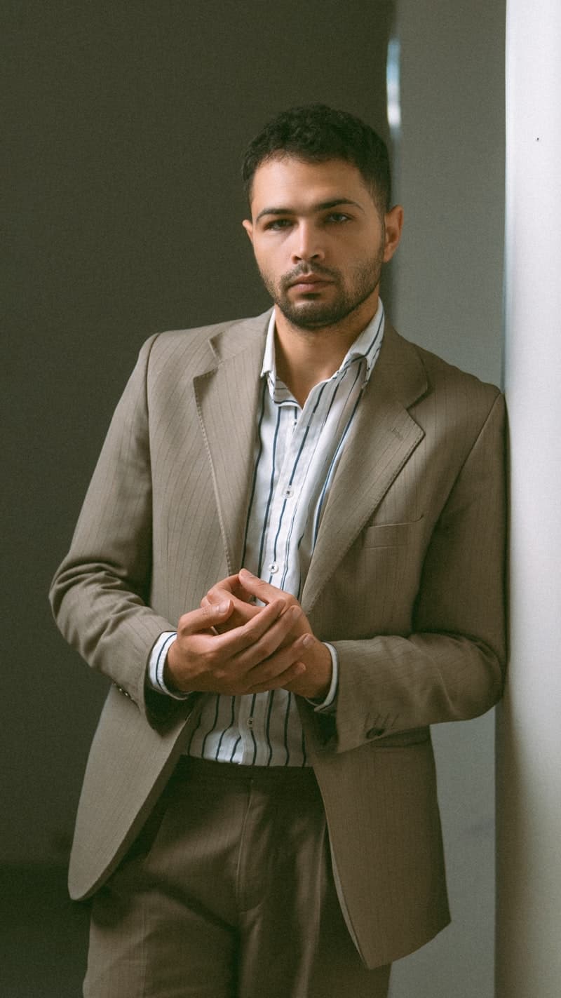 A man in a suit leaning against an office wall