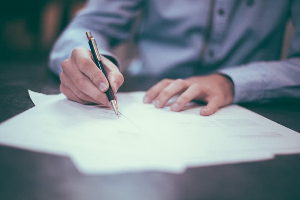 A hand drafting a document with a fountain pen