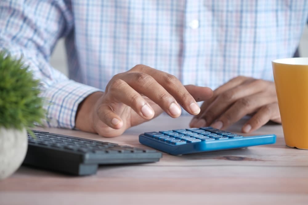 A person working a calculator at a desk with paperwork