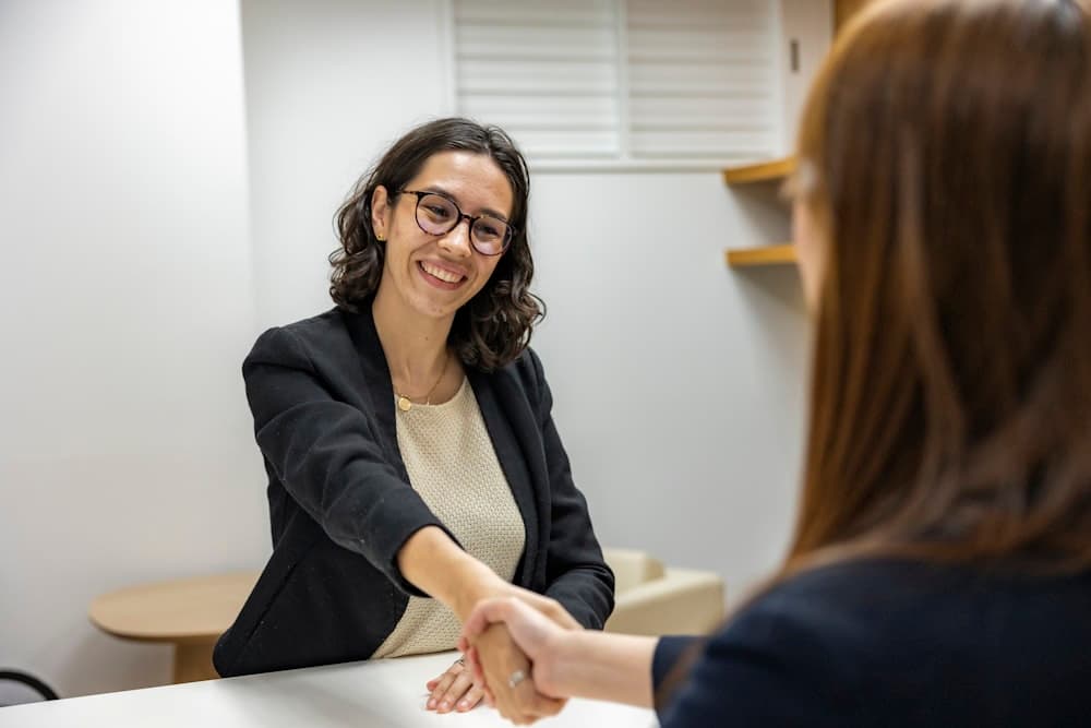 Two people shaking hands across a meeting table