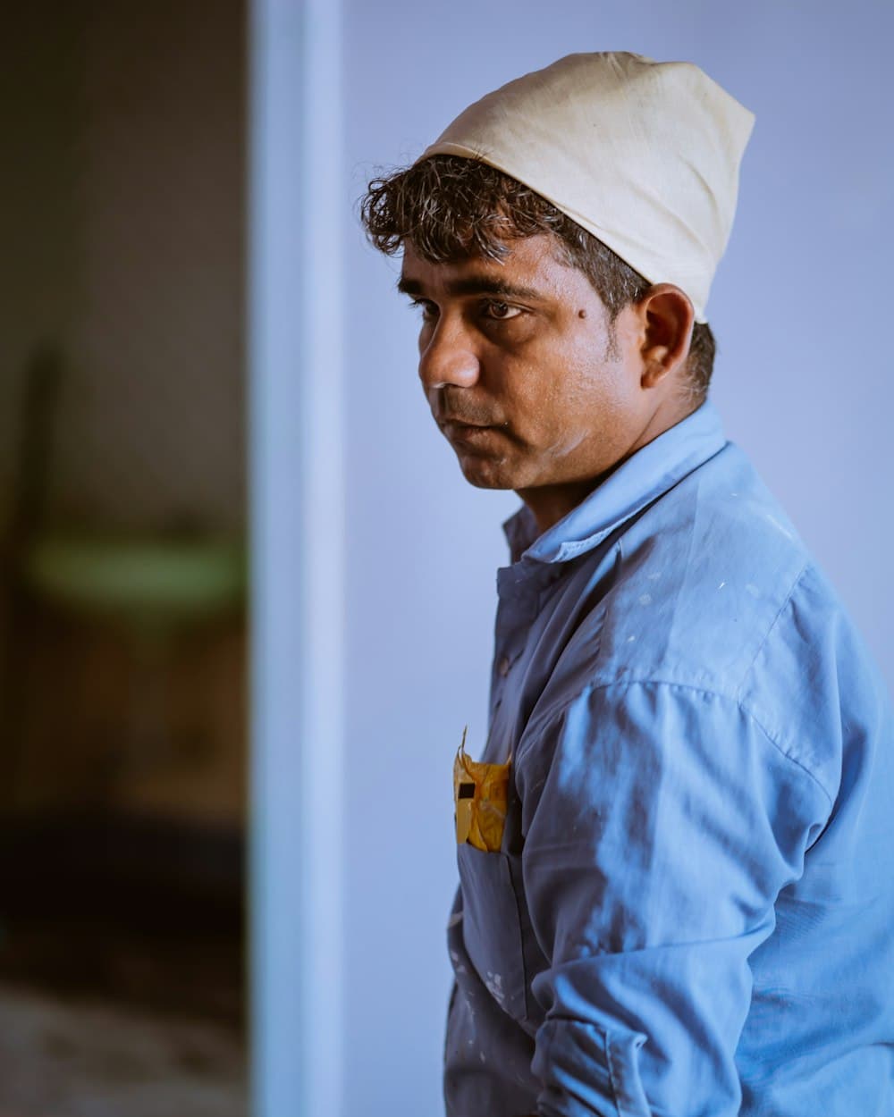 A man in a blue work shirt and cap on a job site