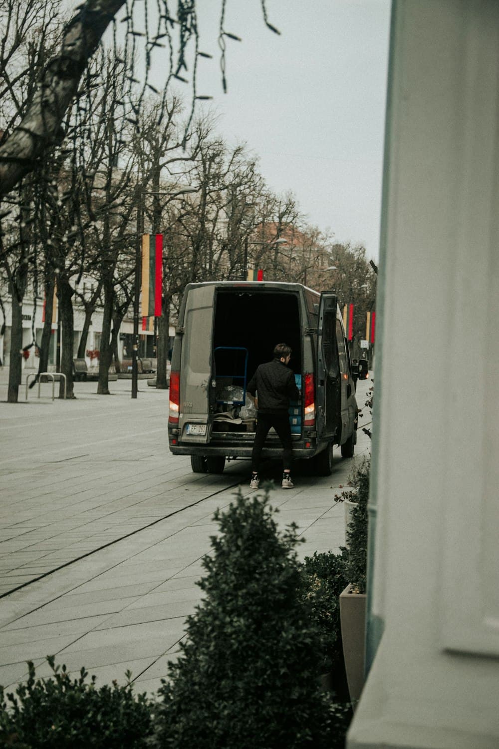 A plumber loading gear through the open rear doors of a van