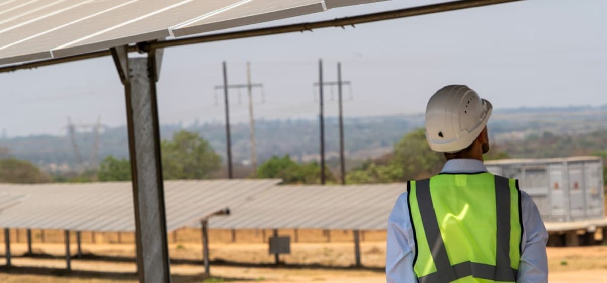 An installer in a hard hat looking over a field of panels
