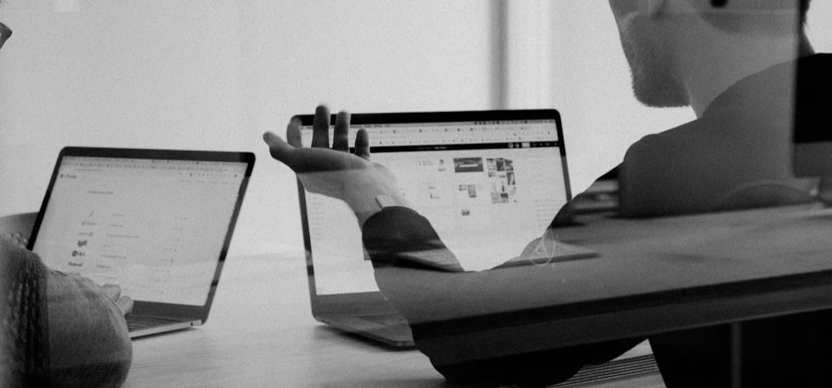 A founder talking through work across 2 laptops at a shared table