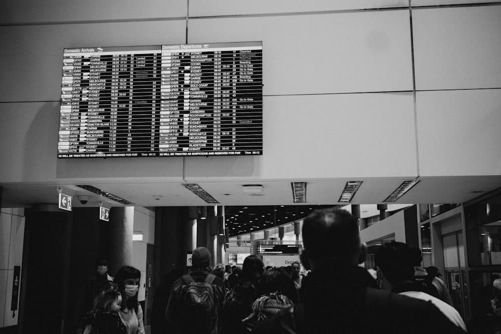 Travelers passing under an airport departures board