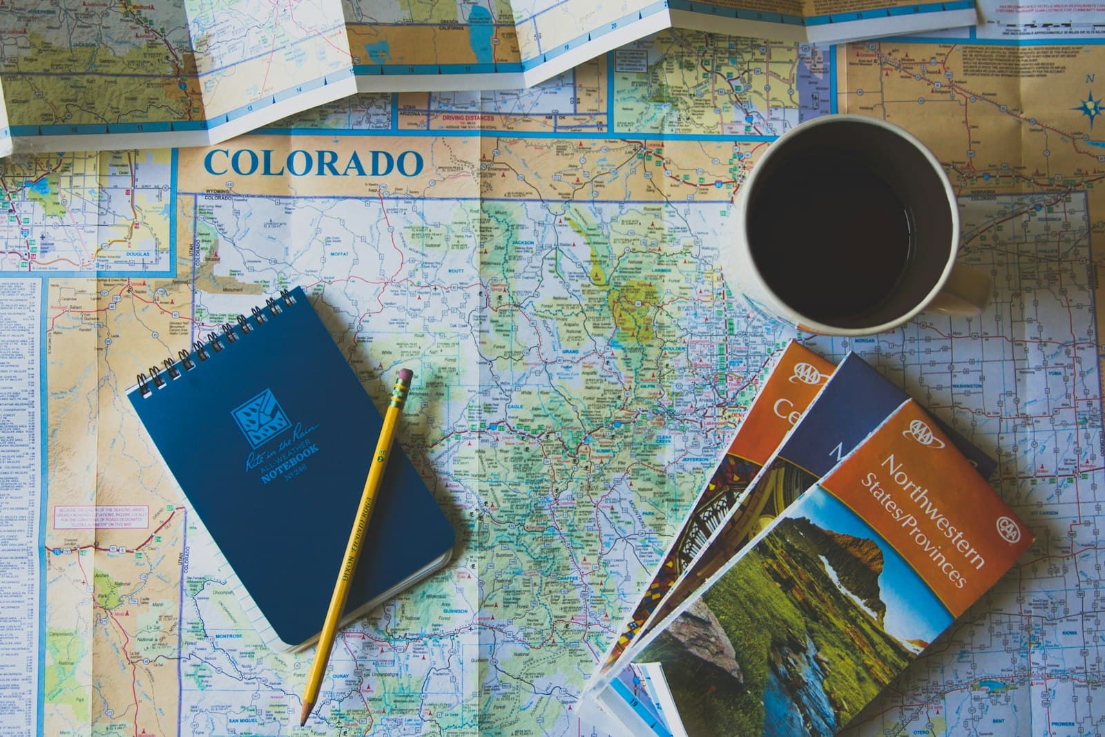 A road map spread on a desk with coffee and guidebooks