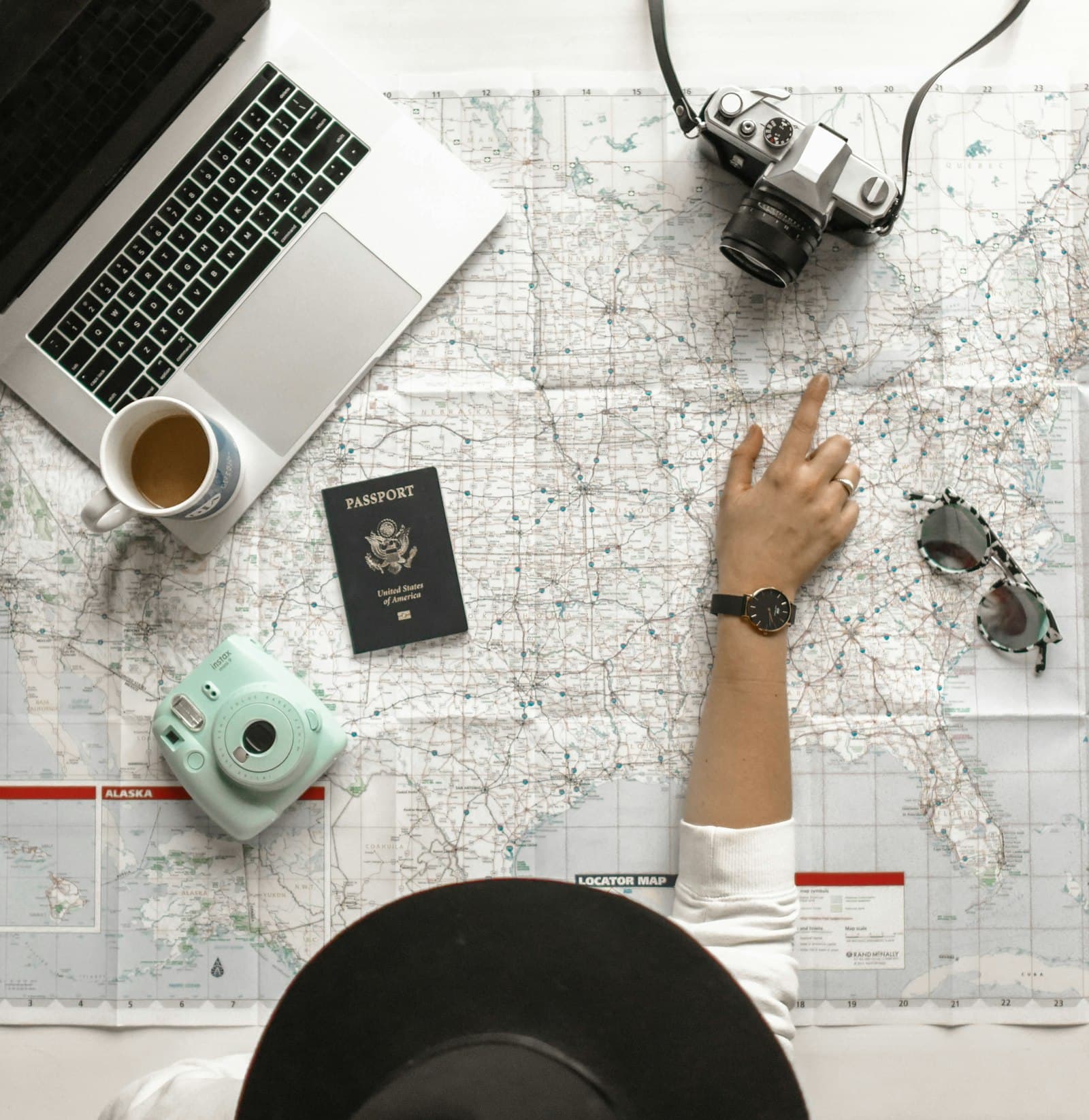 A laptop, passport, and map laid out while a trip is priced