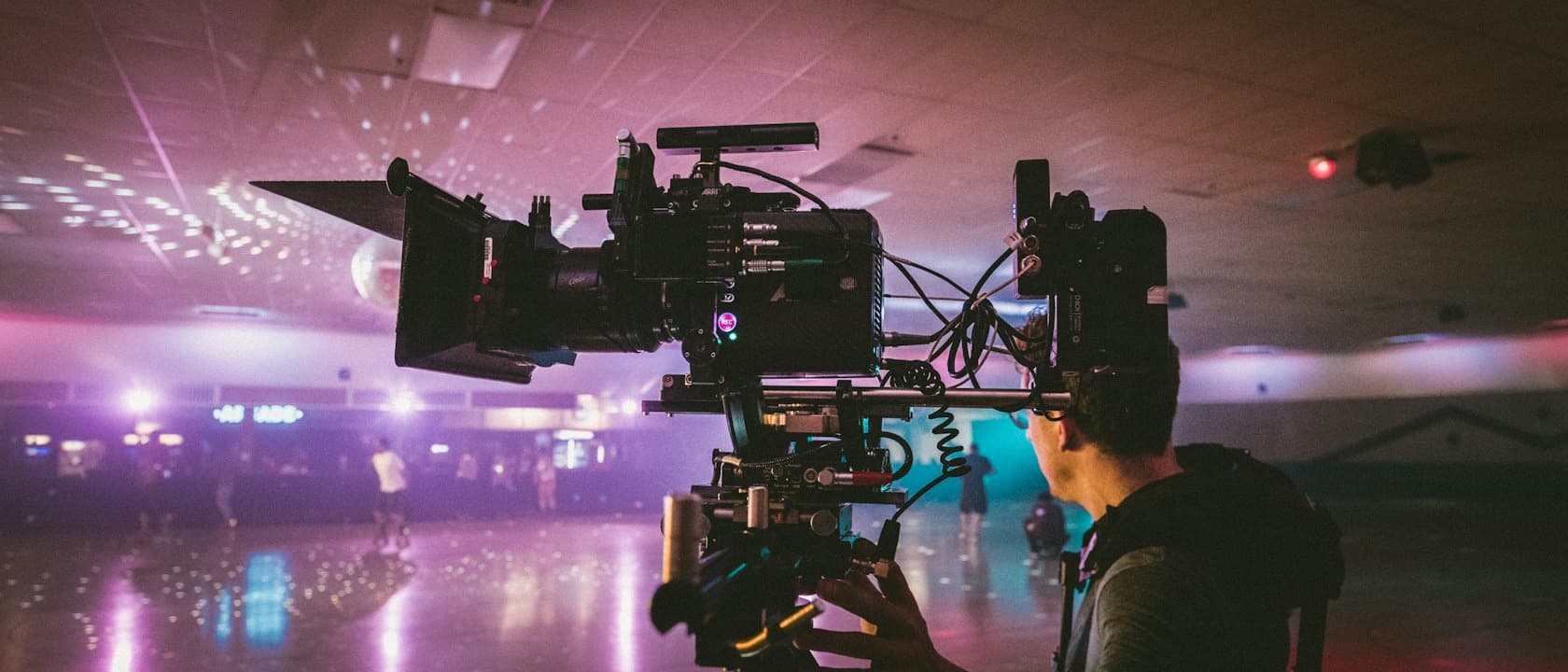 A camera operator lining up a cinema rig inside a roller rink