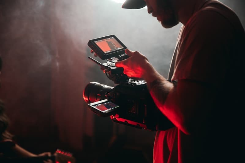 A camera operator checking a monitor in red stage light