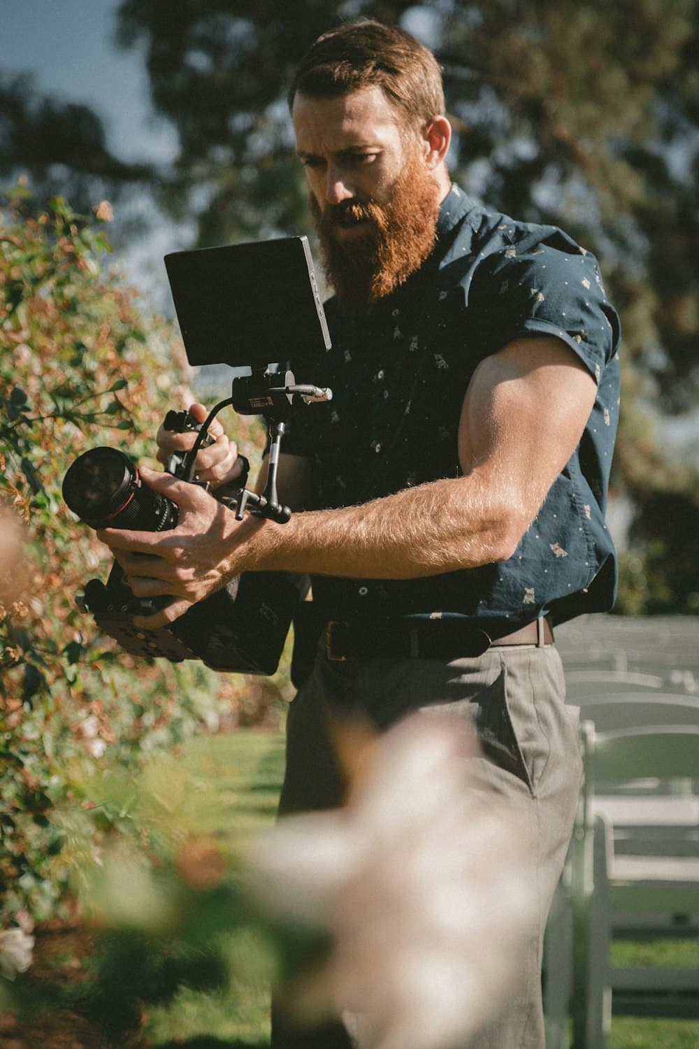 A videographer working a gimbal in a garden ceremony